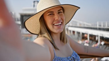 Şapkalı gülümseyen kadın deniz peronlu bir yolcu gemisinde tatilin tadını çıkarıyor..