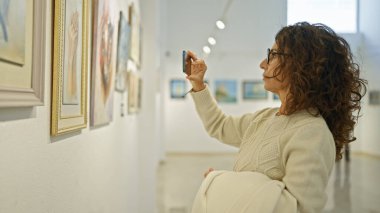 Resim galerisinde resim çeken olgun İspanyol kadın.