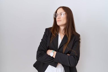 İş ceketi ve gözlük takan güzel esmer kadın kolları çapraz ve kendinden emin bir şekilde yana bakıyor. 