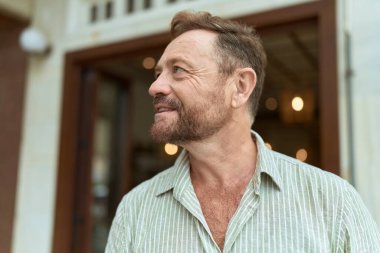 Middle age man smiling confident looking to the side at street