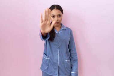 Mavi pijama giyen genç Arap kadın avuç içiyle şarkı söylemeyi kesiyor. Yüzünde olumsuz ve ciddi bir jest olan uyarı ifadesi. 