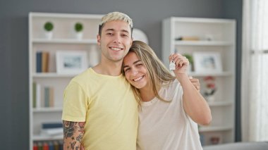 Güzel bir çift, ellerinde anahtarlarla birbirlerine sarılıyorlar.