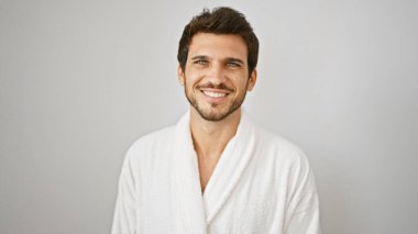 Beyaz bornozlu sakallı yakışıklı genç adam soyutlanmış beyaz arka plana gülümsüyor.