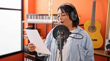 Gitar geçmişi olan İspanyol bir kadın mikrofona şarkı söylüyor.