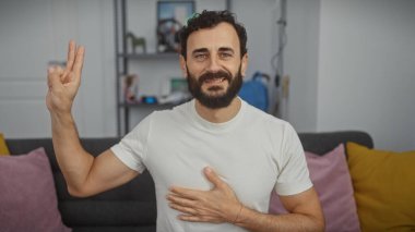 Beyaz gömlekli, sakallı, orta yaşlı yakışıklı bir adam sıcak bir oturma odasında söz veriyor..