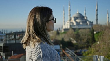 Düşünceli bir kadın İstanbul 'daki terastan ikonik mavi camiye hayran, seyahat ve mimari sergileniyor..