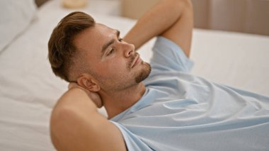 Yatakta sakallı, sakin bir yatak odası sahnesini tasvir eden rahat genç bir adam..