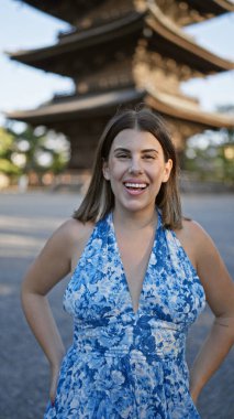 Güzel İspanyol kadın ayakta, güvenle gülümsüyor Japonya 'nın To-ji tapınağının önünde, mutluluk ve kaygısız neşe saçıyor, dostça ifadesi bu Kyoto parkını daha da eğlenceli hale getiriyor..