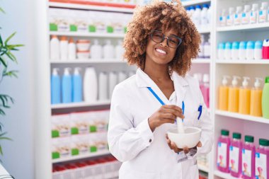 Afro-Amerikan kadın eczacı gülümsemesi eczanede karışımı yapıyor.