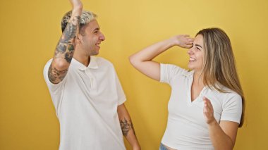 Güzel çift gülümsüyor, kendinden emin beşlik çakıyor izole edilmiş sarı arka planda kutlama yapıyorlar.