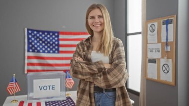 Blonde woman smiles confidently with arms crossed in a usa voting center with ballot box and american flag. clipart