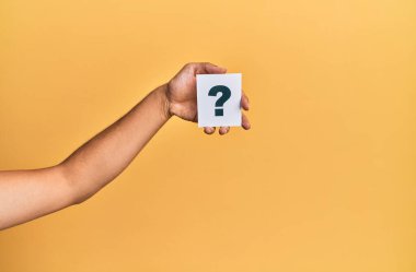 Hand of caucasian man holding paper with question mark over isolated yellow background