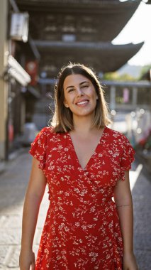 Güzel İspanyol kadın neşeyle gülümsüyor, gururla poz veriyor, eski geleneksel lejyon sokaklarında duruyor, Kyoto, neşeli, kaygısız doğası eğlence dolu bir Japon macerası için parıldıyor..