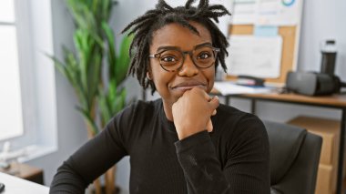 Modern bir ofiste gülümseyen gözlüklü Afrikalı Amerikalı kadın..