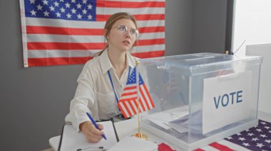 Genç bir kadın, Amerikan bayrağı geçmişi olan bir Amerikan seçim merkezini denetliyor..