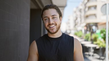 Sokakta kendinden emin gülümseyen İspanyol genç adam.