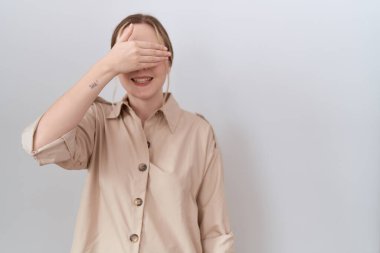 Gündelik tişört giyen genç beyaz bir kadın. Gülümsüyor ve elleri yüzün üzerinde gülüyor. Şaşırtmak için gözleri örtüyor. kör kavram. 