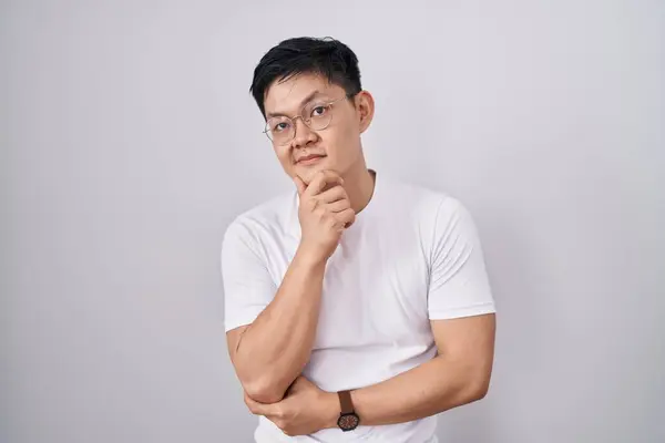 Joven Hombre Asiático Pie Sobre Fondo Blanco Con Mano Barbilla —  Fotos de Stock