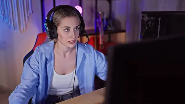 stock image Focused young woman using computer in a gaming room at night, showcasing technology and lifestyle.