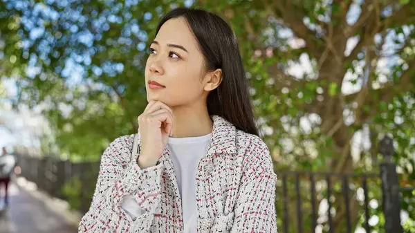 Thoughtful Asian Woman Casual Attire Posing Outdoors Lush City Park — Stock Photo, Image