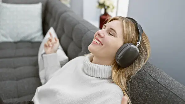 Blonde Woman Relaxing Closed Eyes Wearing Headphones Sofa Cozy Living — Stock Photo, Image