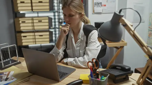 在室内侦探办公室的笔记本电脑上工作的专注的高加索女人 — 图库照片