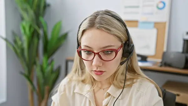 聚焦的年轻高加索女性 戴着眼镜和耳机 在现代化的办公环境中工作 — 图库照片
