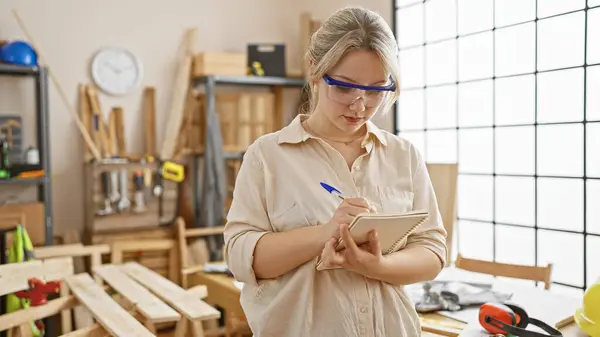 Focused Young Woman Taking Notes Bright Carpentry Workshop Surrounded Woodworking — Stock Photo, Image