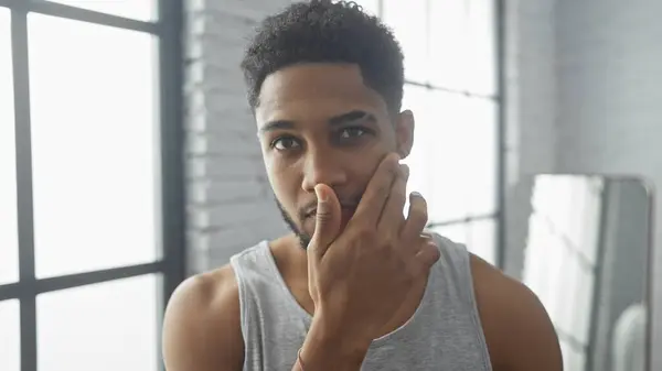 stock image A thoughtful african american man poses in a modern home's living room, exuding casual sophistication.