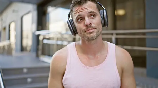 stock image Handsome latino man with headphones in urban outdoor setting looking thoughtful