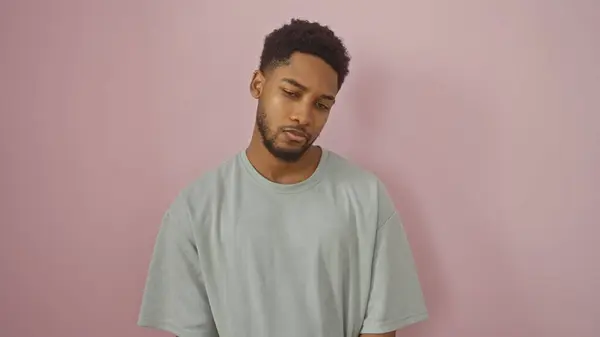 stock image Portrait of a contemplative young african american man against a pink background, exuding a sense of introspection and casual style.
