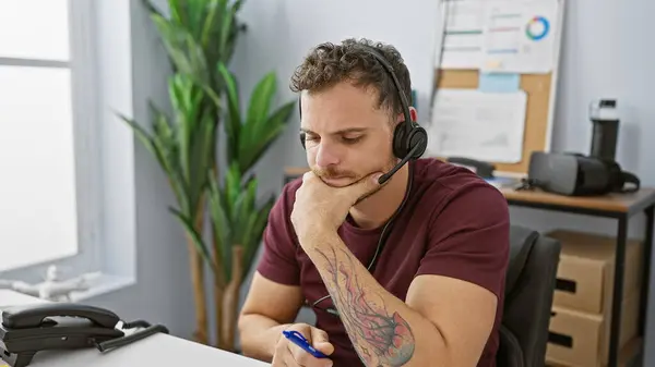 Pensive Young Hispanic Man Beard Wearing Headset Modern Office Setting — Stock Photo, Image
