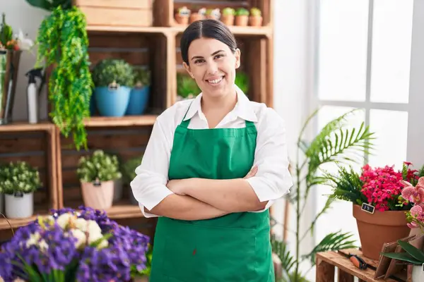 Çiçekçide kollarını kavuşturmuş duran kendine güvenen güzel İspanyol kadın çiçekçi.