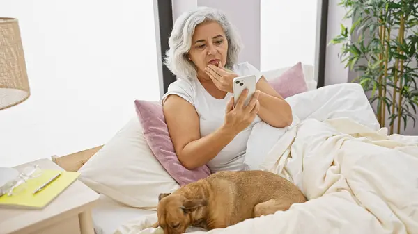 Eine Reife Frau Blickt Überrascht Auf Ihr Handy Bett Während — Stockfoto