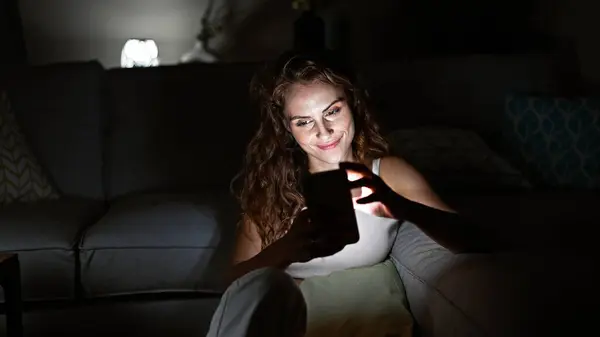 Młoda Biała Kobieta Zabawia Się Domu Angażując Się Swoim Smartfonem — Zdjęcie stockowe