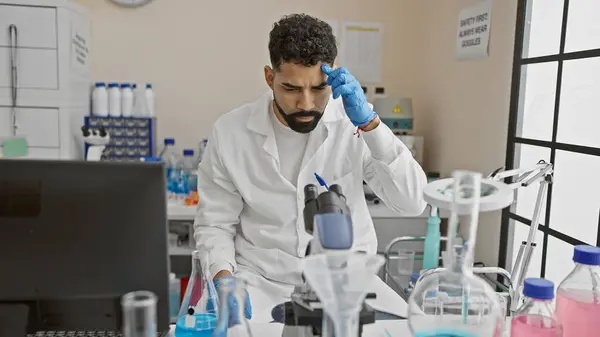 実験室のコートの若い男性は 研究室で科学機器の最中に集中を示しています — ストック写真