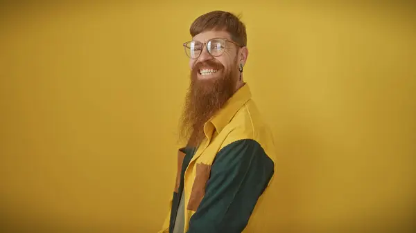 Ein Lächelnder Bärtiger Rotschopf Mit Brille Posiert Selbstbewusst Vor Gelbem Stockfoto