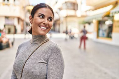 Young beautiful hispanic woman smiling confident looking to the side at street