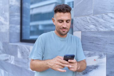 Sokakta akıllı telefon kullanan, kendine güvenen genç bir İspanyol.