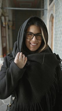 Siyah şallı ve gözlüklü gülümseyen genç bir İspanyol kadın İstanbul 'daki tarihi Topkapı Sarayı' nın içinde duruyor..