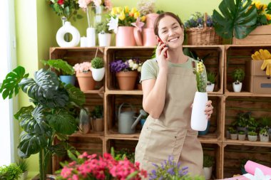 Çiçekçide elinde çiçeklerle konuşan güzel bir kadın.
