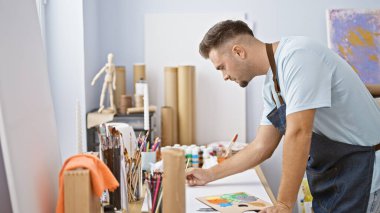 Parlak bir sanat stüdyosunda sakallı düşünceli bir adam..