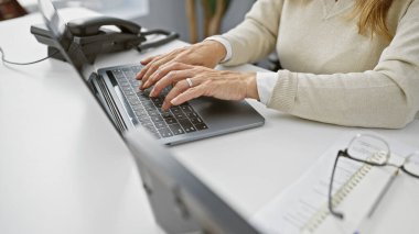 Modern ofiste dizüstü bilgisayarda çalışan yetişkin bir kadın güzel ve odaklanmış bir profesyoneli canlandırıyor..