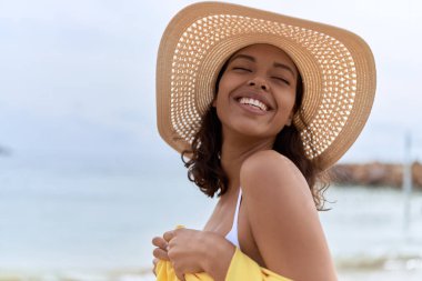 Young african american woman smiling confident wearing summer hat and bikini at beach