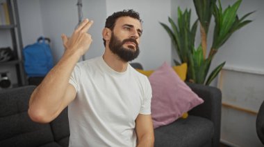 Sakallı, orta yaşlı bir adam oturma odasında kafasına silah dayayıp hayal kırıklığını ya da umutsuzluğu ifade eder..