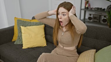 Şaşırmış genç bir kadın, kapalı bir koltukta oturuyor. Yüzündeki ifadeyi bu samimi portreye yansıtıyor..