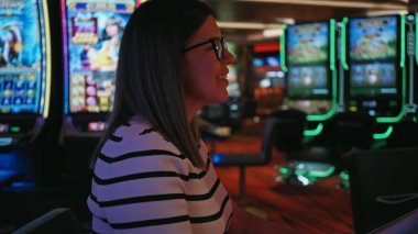 Gözlüklü, neşeli bir kumarhanede kumar oynayan gülümseyen bir kadın.