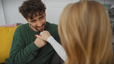 Bir kadın ve bir erkek romantik bir evde, evdeki rahat bir kanepede hassas bir anı paylaşıyorlar..