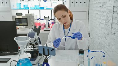 Kafkas kadın bilim adamı mikroskop ve kimyasallarla laboratuvar ortamında araştırma yapıyor.