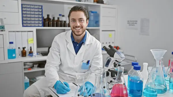 Jovem Cientista Hispânico Escrevendo Relatório Sorrindo Para Laboratório — Fotografia de Stock